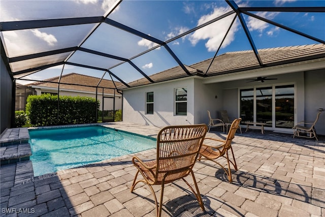 view of pool featuring a patio area, glass enclosure, and ceiling fan