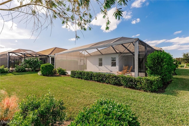 rear view of property featuring a yard, a patio, and a lanai