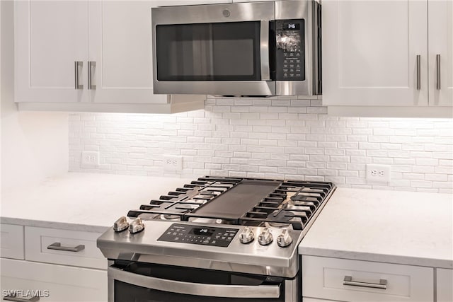 kitchen featuring white cabinets, light stone counters, stainless steel appliances, and tasteful backsplash