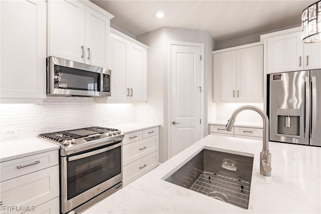 kitchen featuring sink, appliances with stainless steel finishes, pendant lighting, and white cabinetry