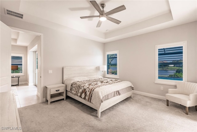 carpeted bedroom with ceiling fan and a tray ceiling