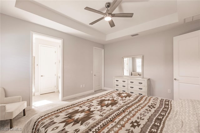 bedroom with ceiling fan, a tray ceiling, and light colored carpet