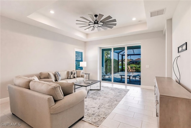 living room with ceiling fan, light tile patterned flooring, and a raised ceiling