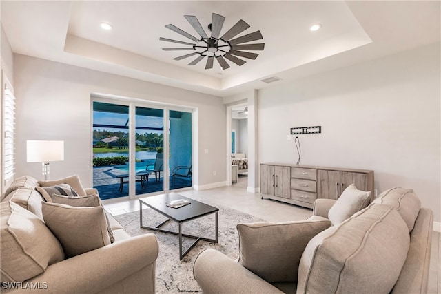 living room featuring a healthy amount of sunlight, a tray ceiling, and ceiling fan