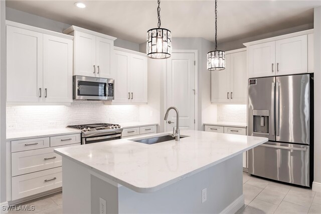 kitchen featuring sink, hanging light fixtures, white cabinetry, stainless steel appliances, and a kitchen island with sink