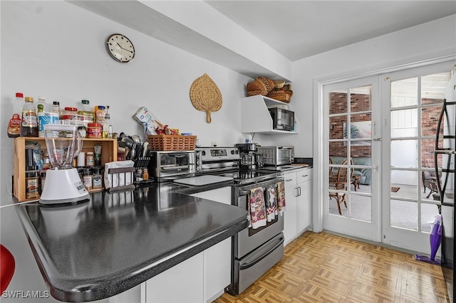 kitchen featuring stainless steel range with electric stovetop, french doors, white cabinets, and light parquet flooring