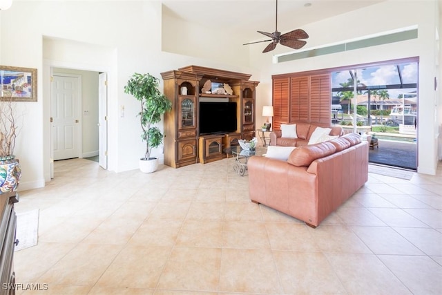 living room featuring ceiling fan, a towering ceiling, and light tile patterned floors