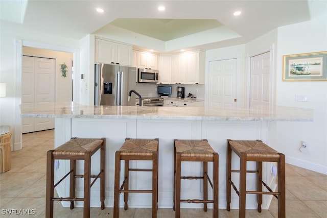 kitchen featuring white cabinets, stainless steel appliances, and a breakfast bar area