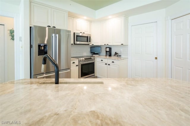 kitchen with white cabinets, light stone counters, and appliances with stainless steel finishes