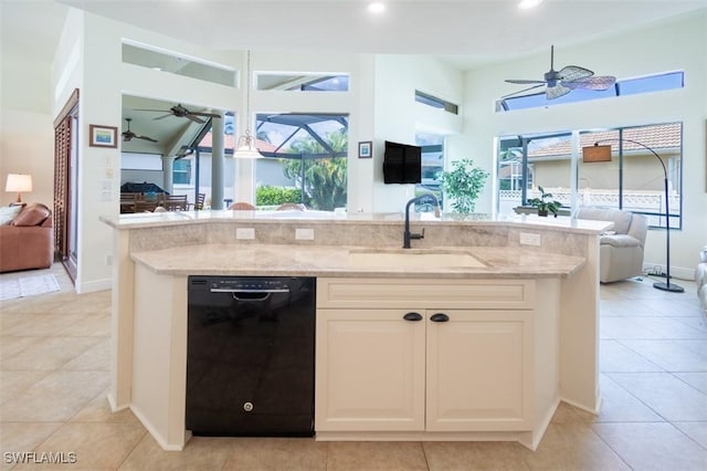 kitchen with light stone counters, sink, light tile patterned floors, white cabinets, and black dishwasher