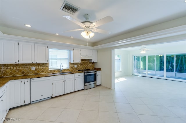 kitchen with backsplash, white dishwasher, sink, white cabinets, and stainless steel range oven