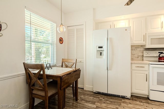 kitchen featuring decorative backsplash, white appliances, white cabinetry, hardwood / wood-style flooring, and hanging light fixtures