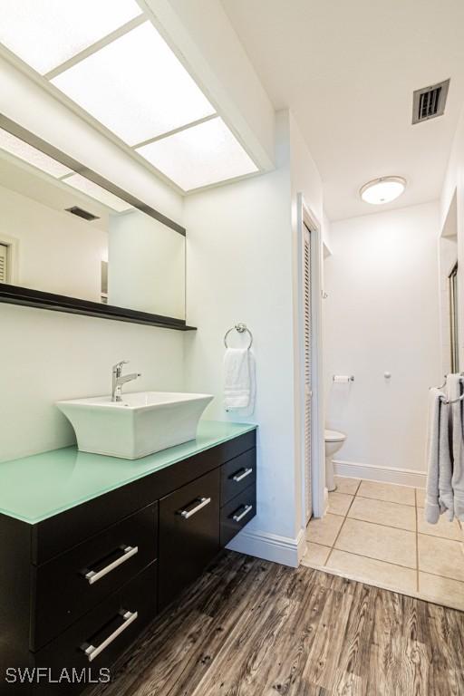 bathroom with hardwood / wood-style flooring, toilet, and vanity