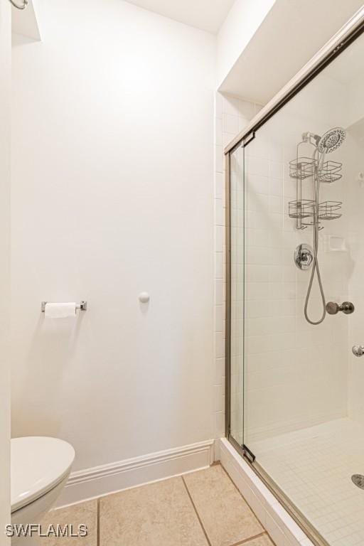 bathroom with a shower with shower door, toilet, and tile patterned flooring