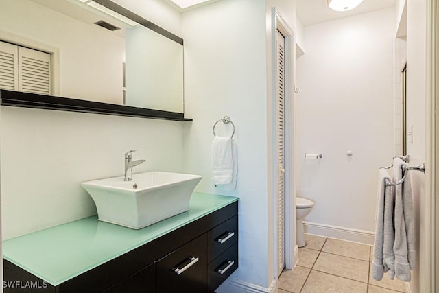 bathroom with toilet, vanity, and tile patterned flooring