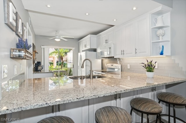 kitchen featuring ceiling fan, sink, tasteful backsplash, kitchen peninsula, and white cabinets