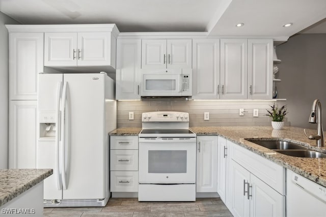 kitchen with white appliances, white cabinets, sink, tasteful backsplash, and light stone counters