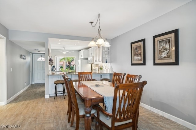 dining space with light hardwood / wood-style floors and ceiling fan with notable chandelier