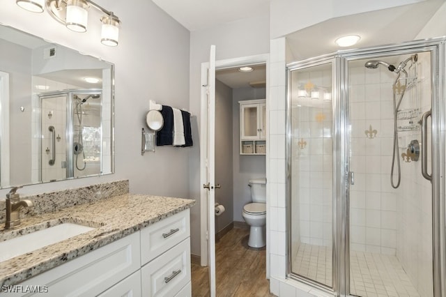 bathroom featuring hardwood / wood-style floors, vanity, toilet, and a shower with shower door