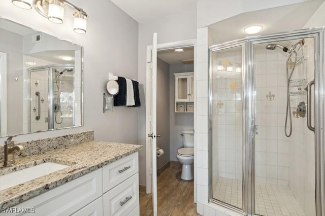 bathroom with a shower with door, vanity, hardwood / wood-style flooring, and toilet