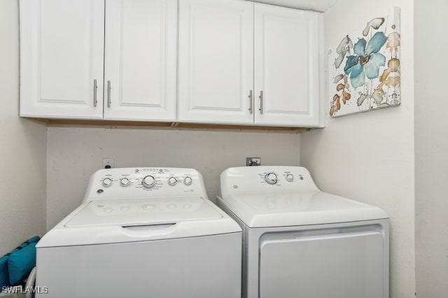 clothes washing area with cabinets and washing machine and clothes dryer