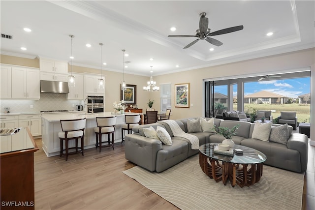 living room with crown molding, light hardwood / wood-style flooring, and ceiling fan with notable chandelier