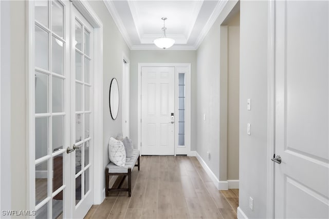 foyer with french doors, light hardwood / wood-style floors, ornamental molding, and a tray ceiling