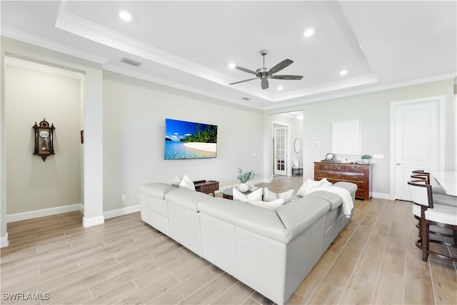 living room featuring a tray ceiling, light hardwood / wood-style floors, and ceiling fan