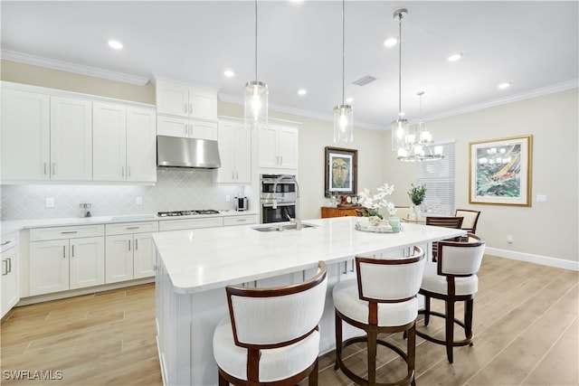 kitchen featuring white cabinetry, appliances with stainless steel finishes, pendant lighting, and a kitchen island with sink