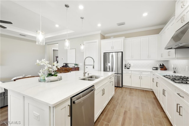 kitchen featuring an island with sink, sink, decorative light fixtures, white cabinetry, and appliances with stainless steel finishes