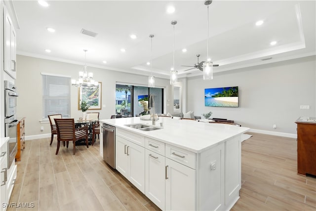 kitchen with sink, white cabinets, hanging light fixtures, and a kitchen island with sink