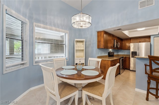 tiled dining space with a towering ceiling and an inviting chandelier