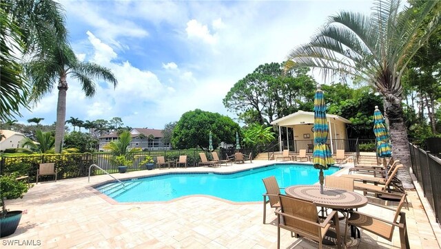 pool with a patio area and fence