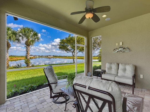 sunroom / solarium featuring a water view and ceiling fan