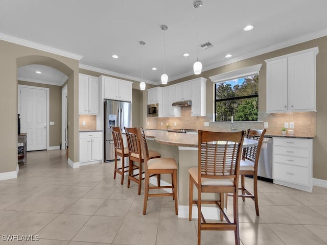 kitchen with a kitchen island, white cabinets, hanging light fixtures, and stainless steel appliances