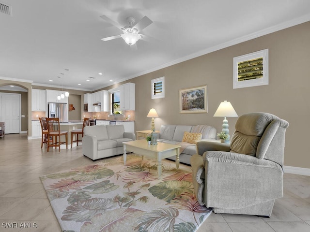 tiled living room with ornamental molding and ceiling fan