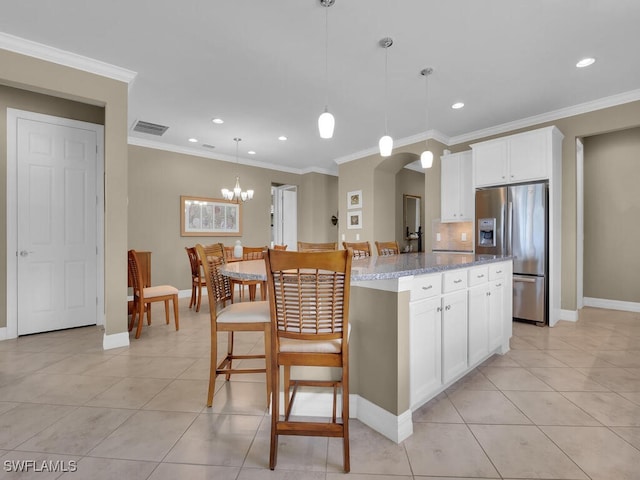 kitchen featuring light stone countertops, a center island, white cabinetry, decorative light fixtures, and stainless steel fridge with ice dispenser