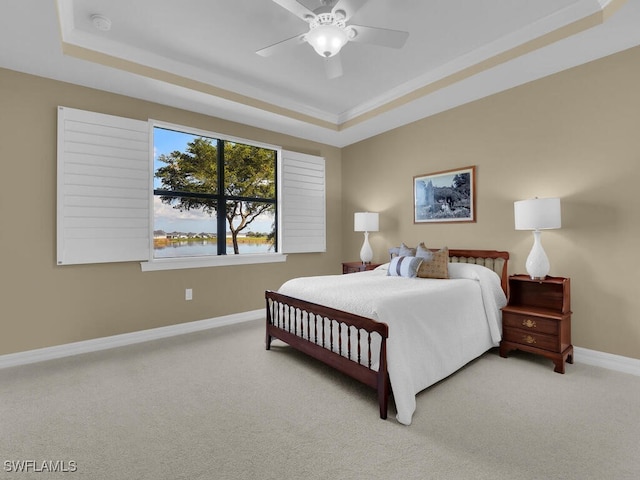 bedroom with a water view, ceiling fan, a tray ceiling, and carpet floors