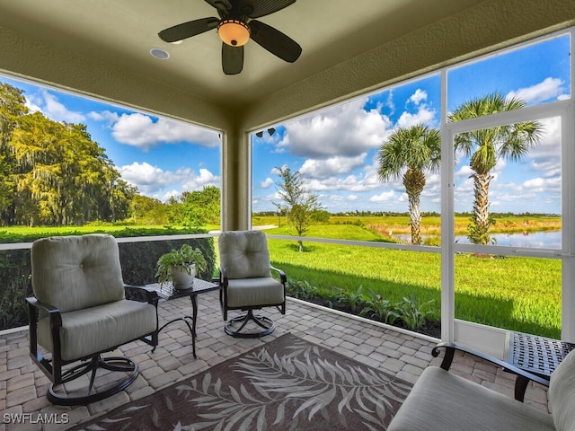 sunroom / solarium with a water view, ceiling fan, and a wealth of natural light