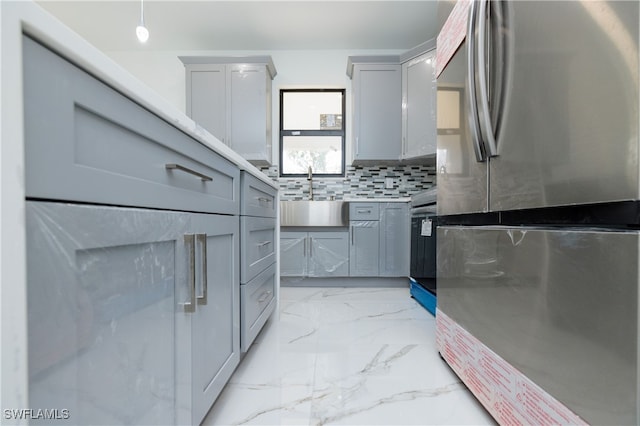 kitchen featuring gray cabinetry, tasteful backsplash, stainless steel refrigerator, and sink