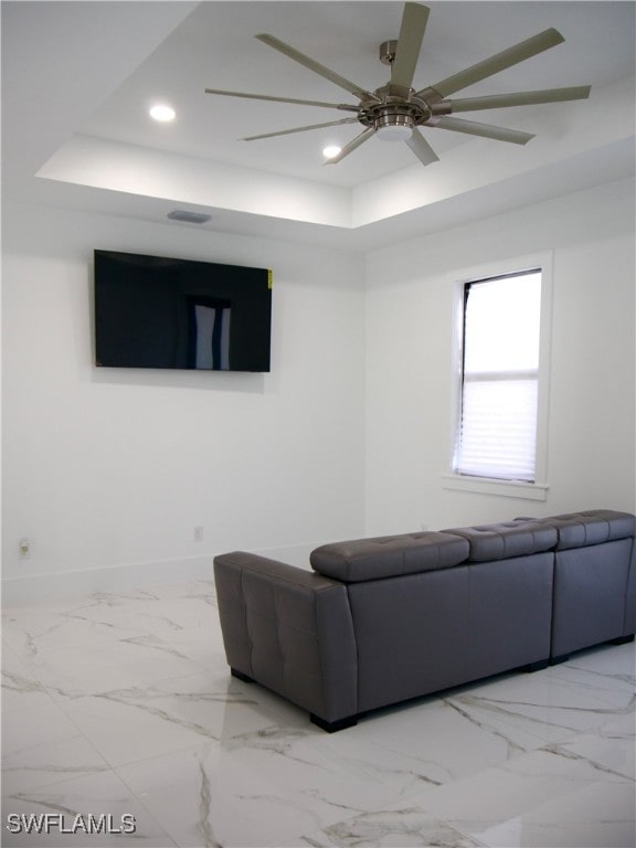 living room featuring a raised ceiling and ceiling fan