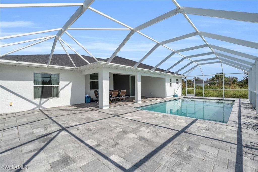 view of pool featuring glass enclosure and a patio