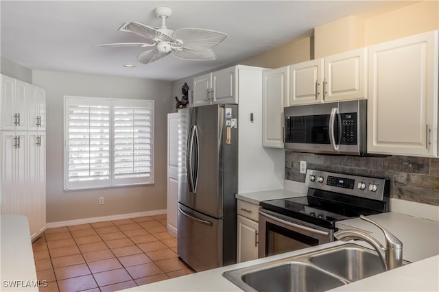 kitchen with decorative backsplash, stainless steel appliances, sink, light tile patterned floors, and white cabinetry