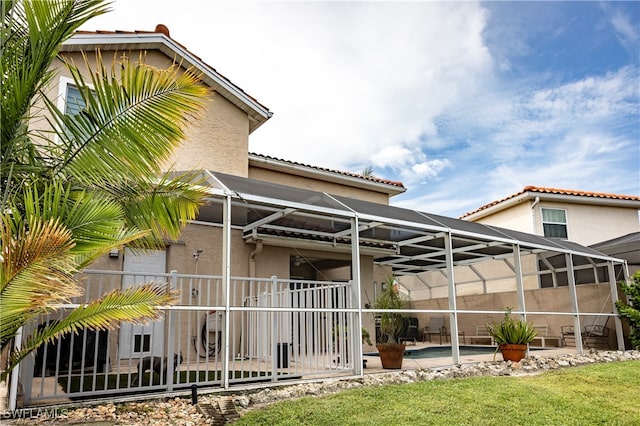 rear view of property with a patio area, a lawn, and a lanai