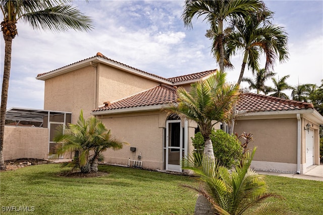 rear view of property with a garage and a lawn