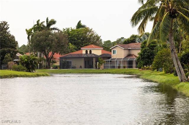 view of front of home with a front lawn, a water view, and glass enclosure