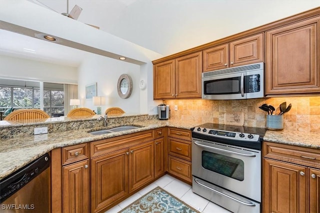 7725 Pebble Creek Cir Unit 8-303, Naples, FL 34108 - kitchen featuring stainless steel appliances, a sink, brown cabinets, light stone counters, and tasteful backsplash