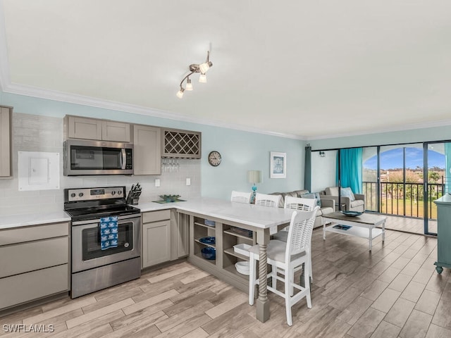 kitchen featuring crown molding, gray cabinets, stainless steel appliances, light countertops, and backsplash