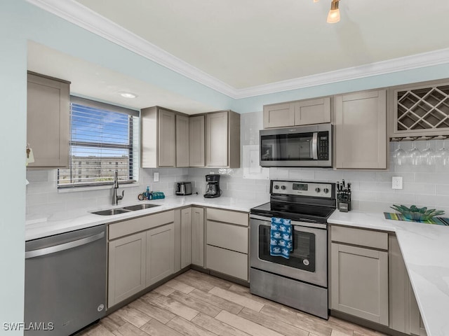 kitchen featuring stainless steel appliances, ornamental molding, sink, and tasteful backsplash