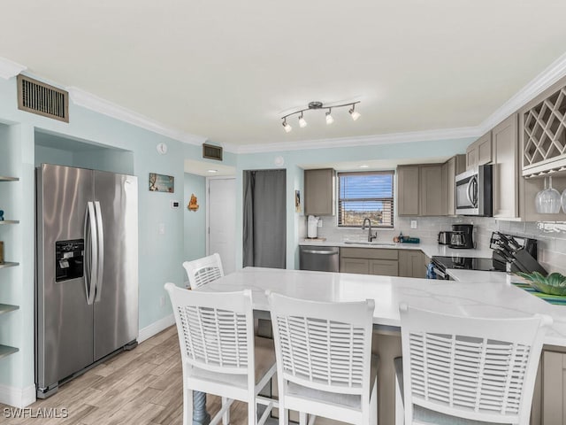 kitchen featuring ornamental molding, stainless steel appliances, visible vents, and a sink